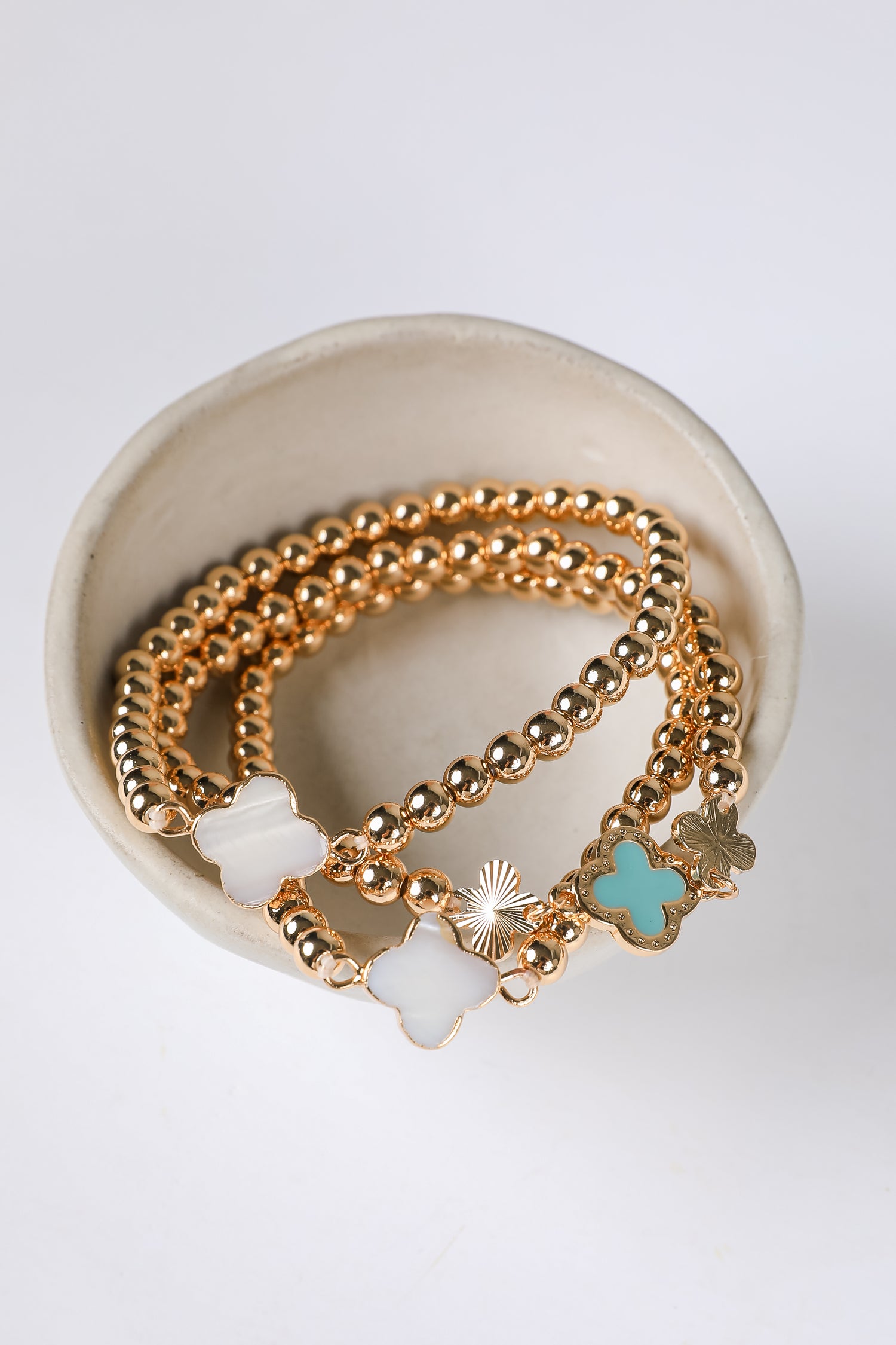 Gold bracelets with charms on a white background