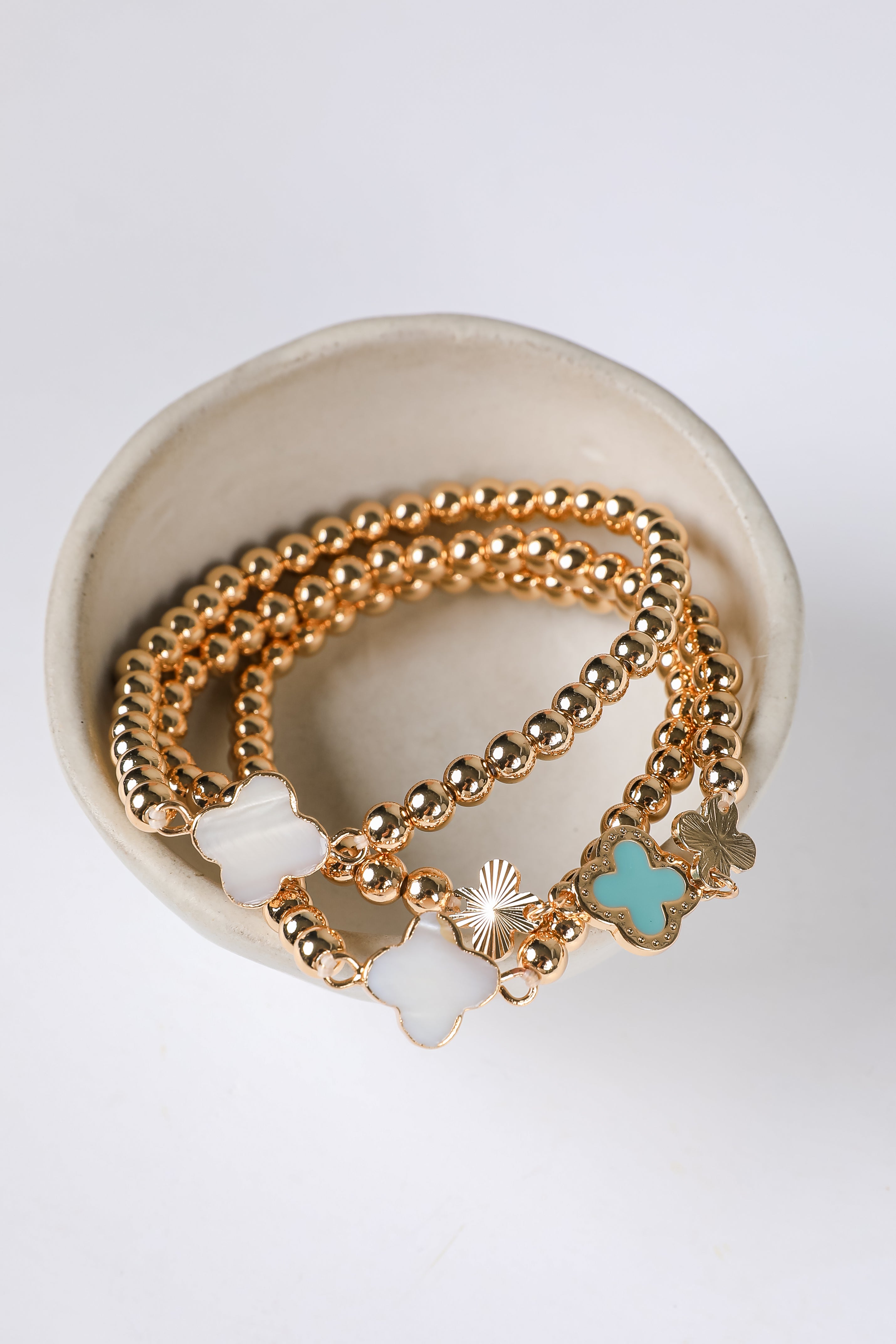 Gold bracelets with charms on a white background