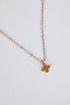 Gold necklace with a small pendant on a light gray background