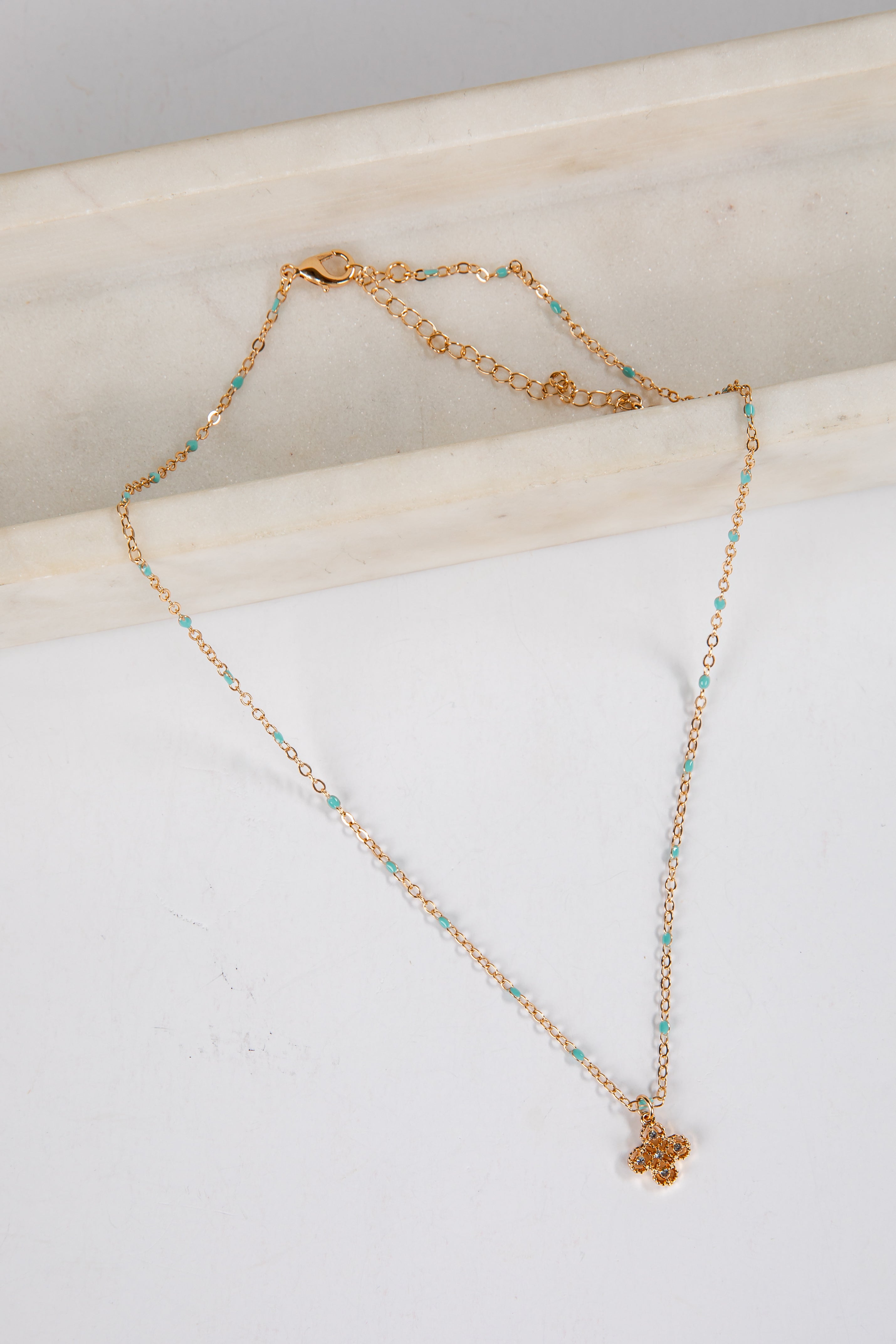 Gold necklace with turquoise beads on a marble surface
