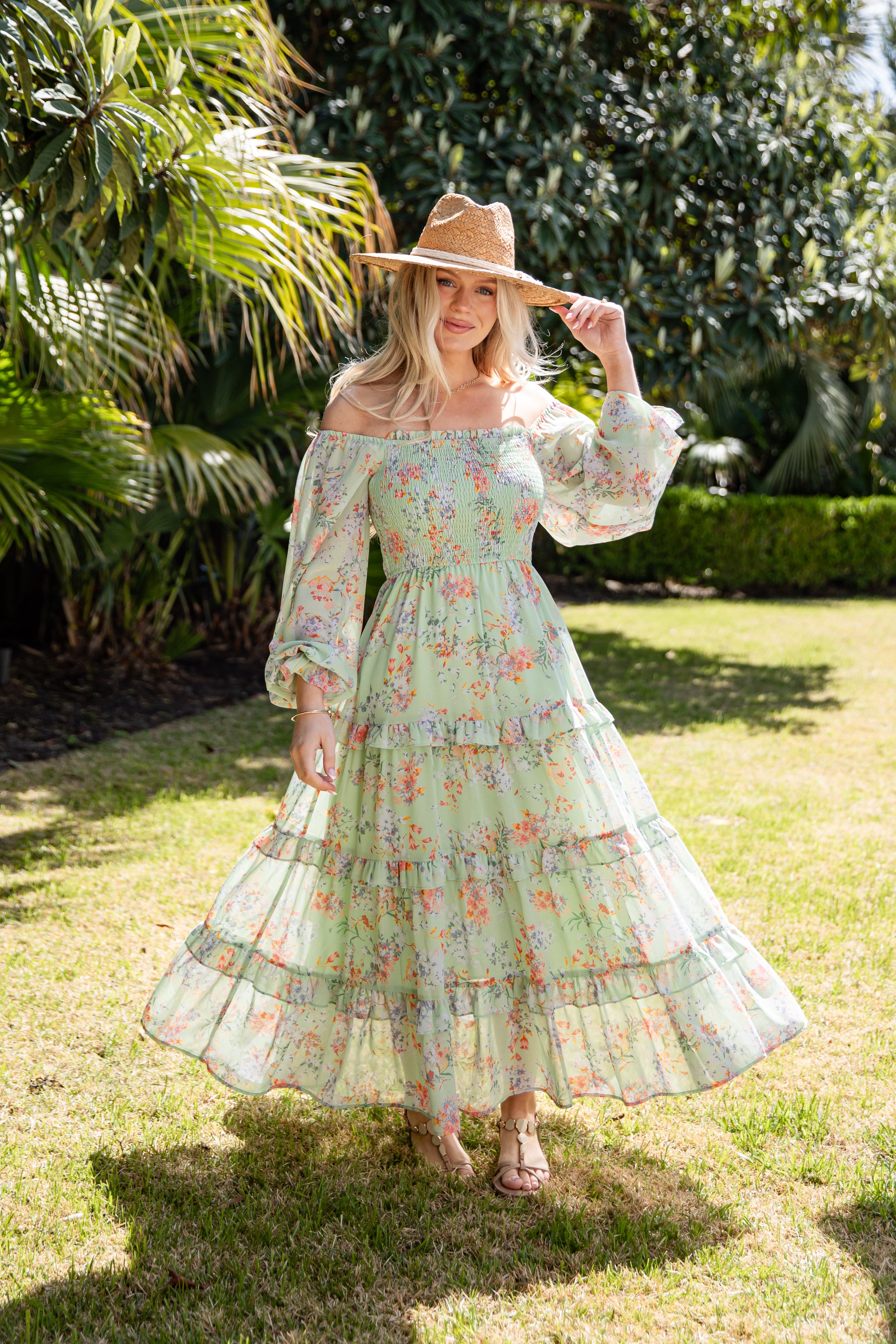 Woman in a floral dress and hat standing in a garden