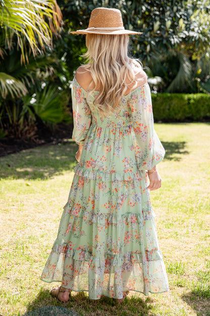 Woman in a floral dress and straw hat standing in a garden
