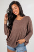 Woman wearing a brown sweater with a pocket on a plain background