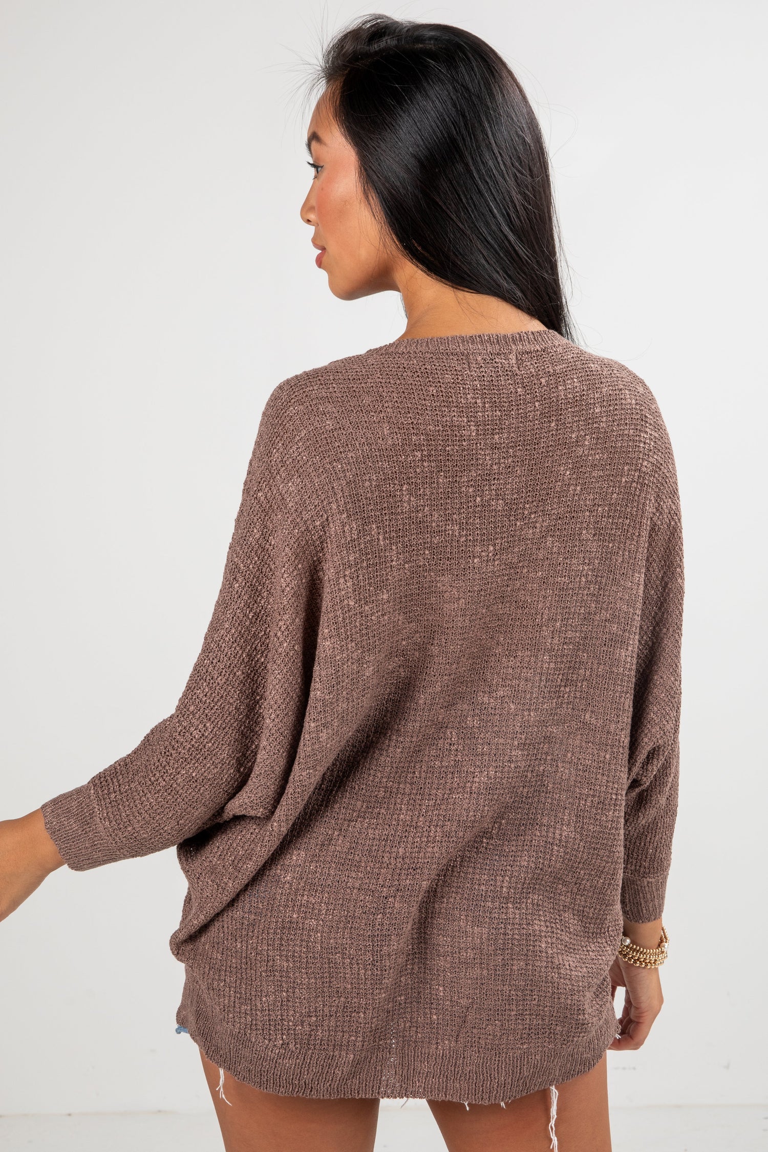 Woman wearing a brown sweater against a white background