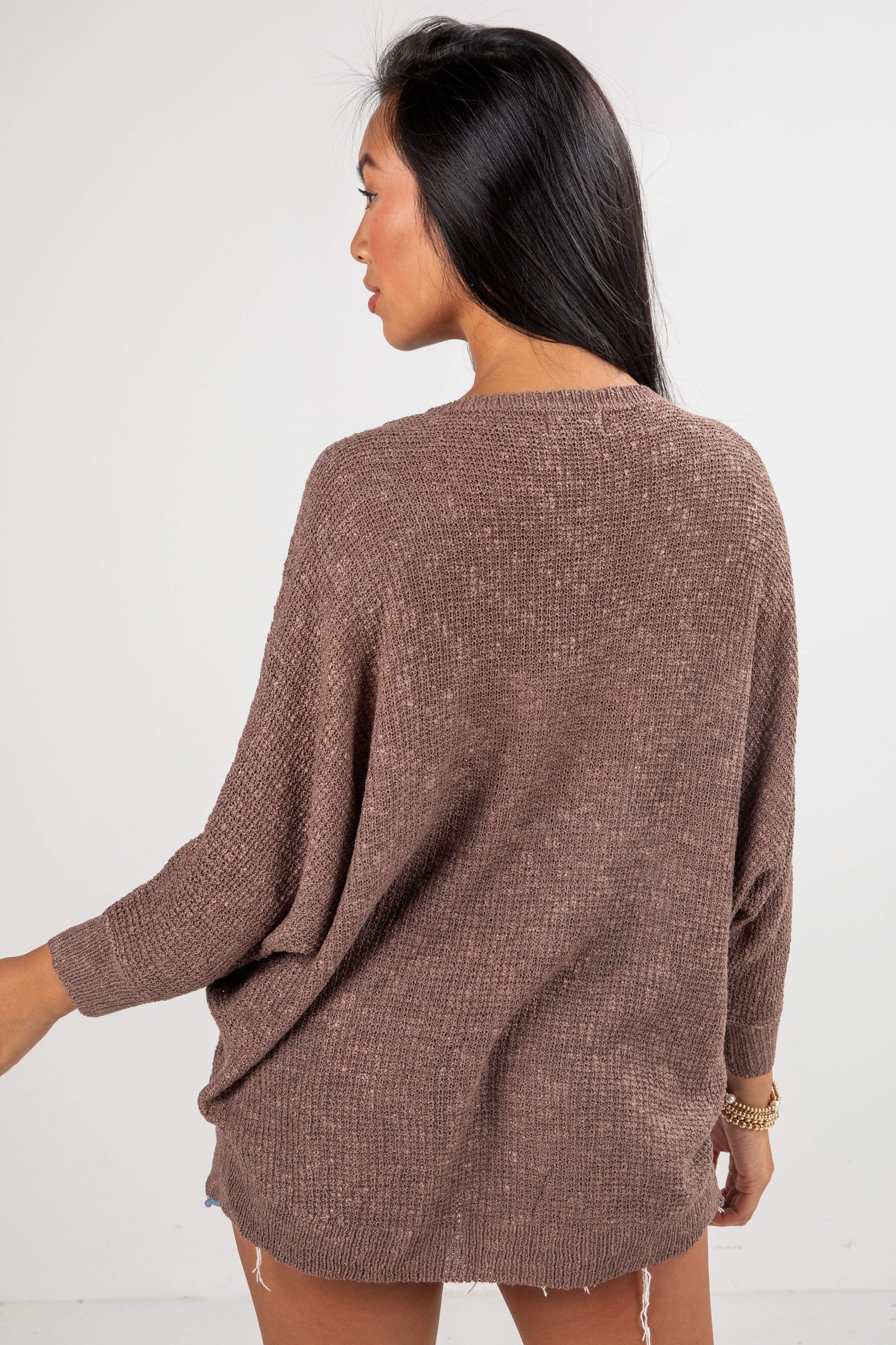 Woman wearing a brown sweater against a white background