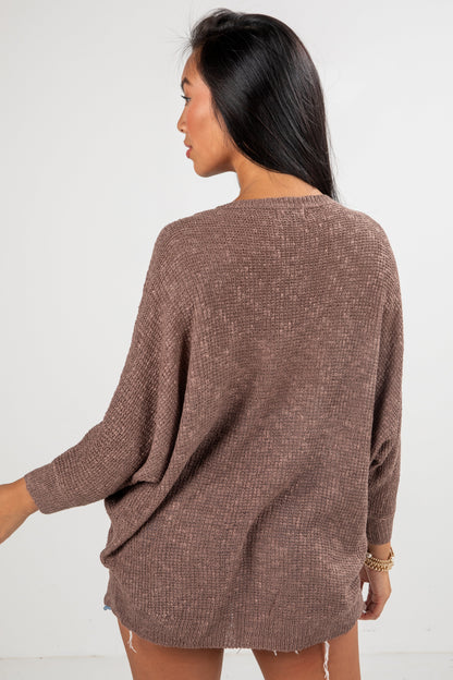 Woman wearing a brown sweater against a white background
