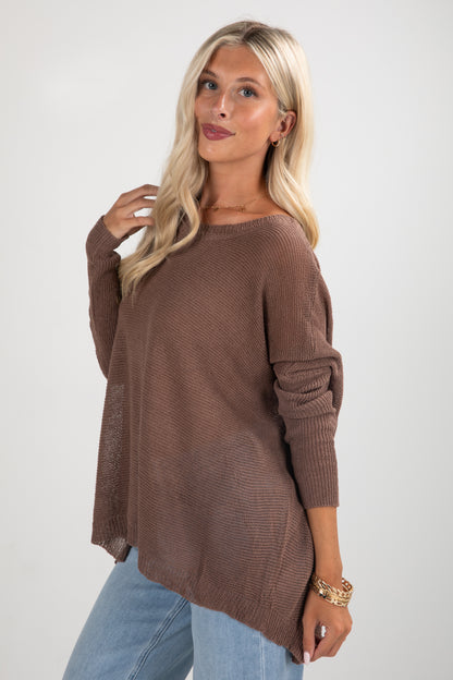 Woman wearing a brown sweater and light blue jeans on a white background