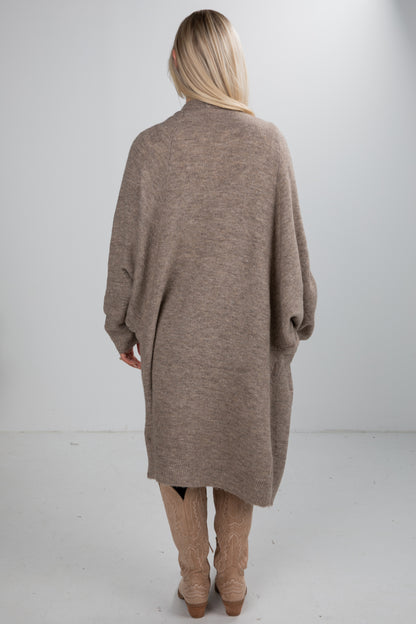 Person wearing a long brown cardigan on a white background