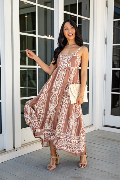 Woman in a patterned dress standing on a wooden deck.