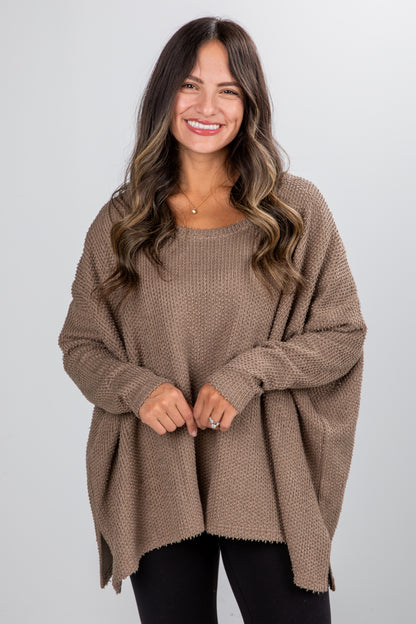 Woman wearing a brown poncho against a white background