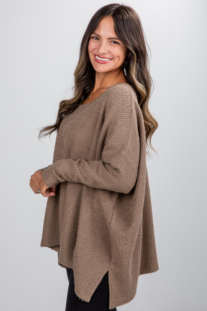 Woman wearing a brown sweater against a white background