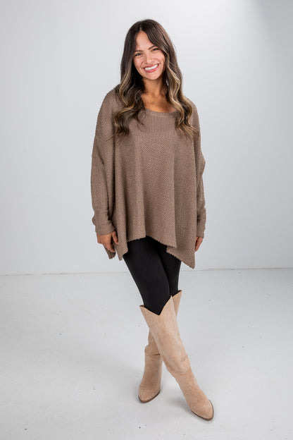 Woman wearing a brown sweater and beige boots on a white background