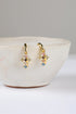 Gold earrings with colorful stones on a white bowl