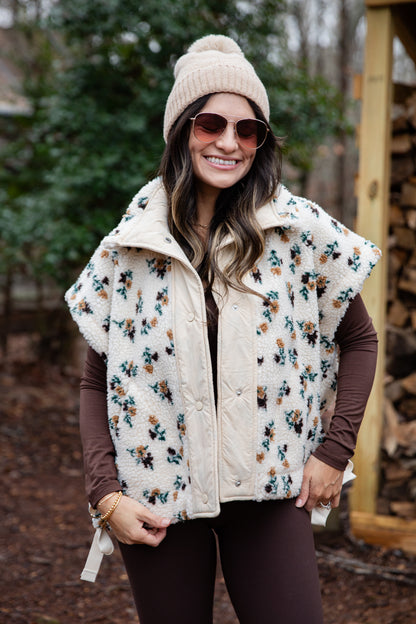 Woman wearing a floral patterned vest and sunglasses outdoors.