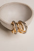 Three gold hoop earrings on a white ceramic dish