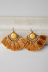 Pair of gold tassel earrings with yellow center on a light gray background