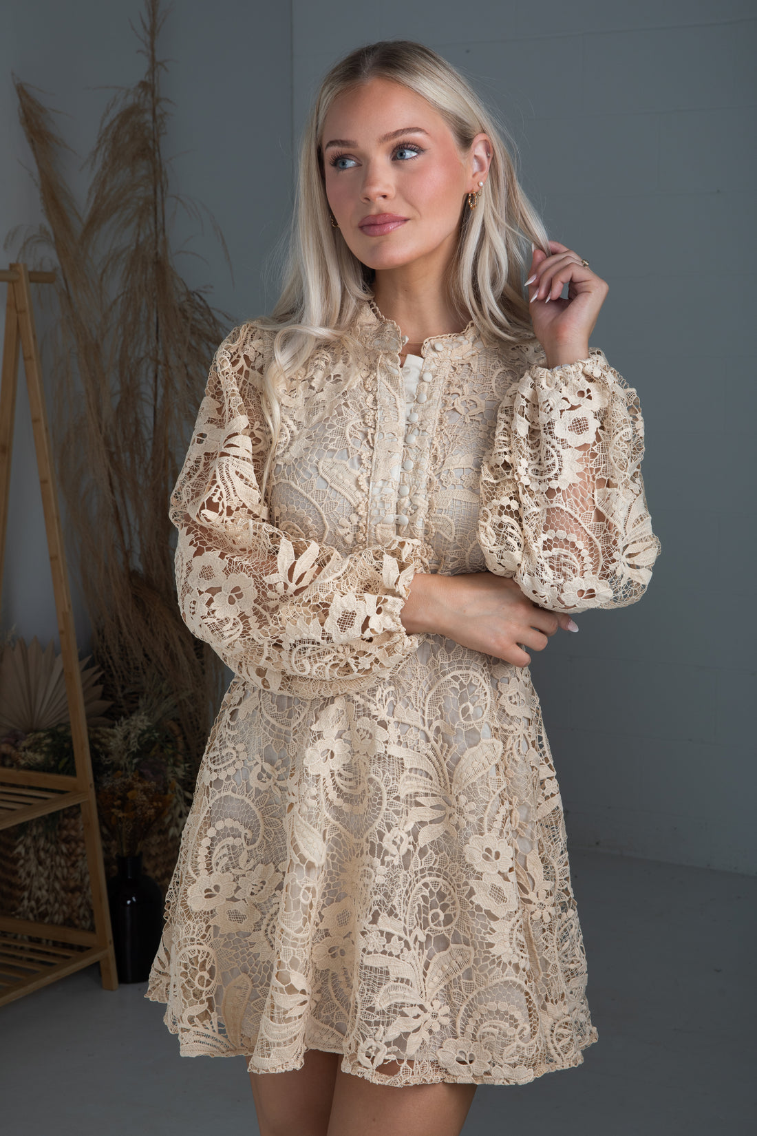 Woman wearing a beige lace dress in a minimal indoor setting