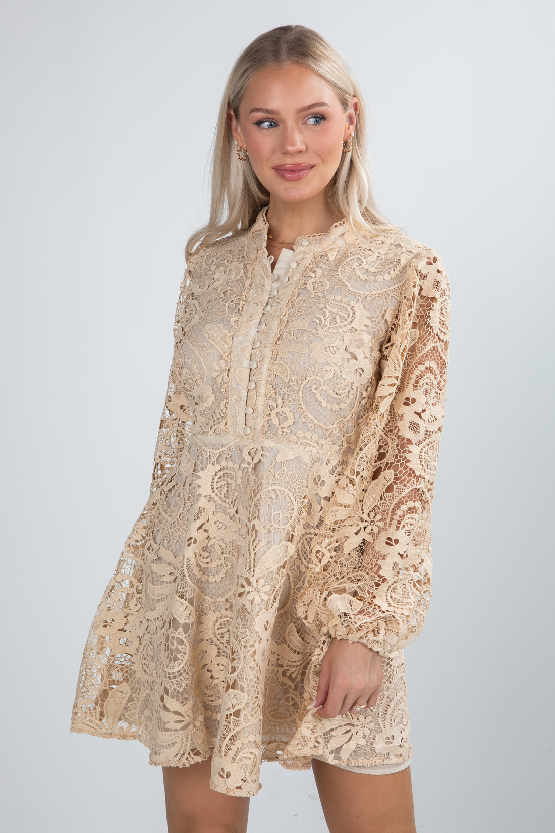 Woman wearing a beige lace dress against a white background