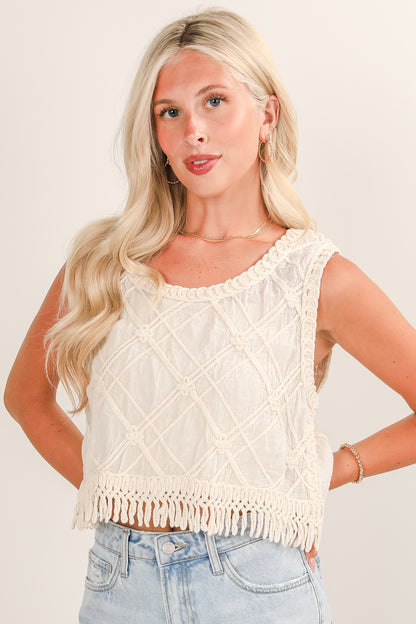 Woman wearing a cream-colored fringe top against a plain background
