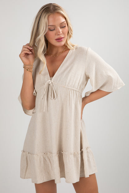 Woman wearing a beige dress against a plain background