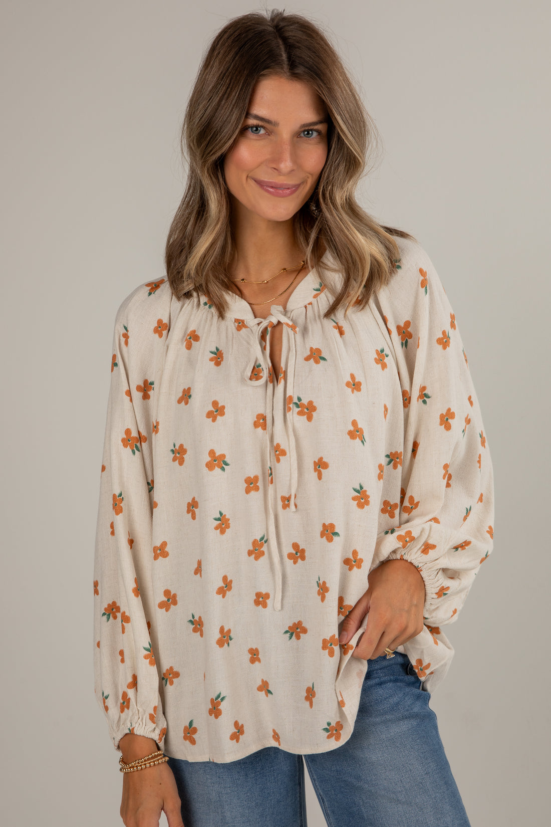 Woman wearing a floral blouse with long sleeves against a plain background