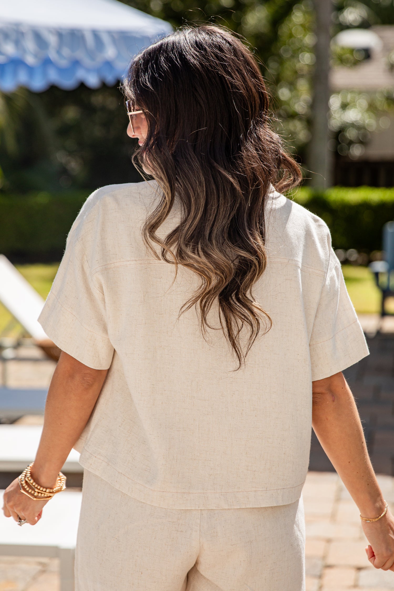 Woman in a beige outfit walking outdoors with a blurred background