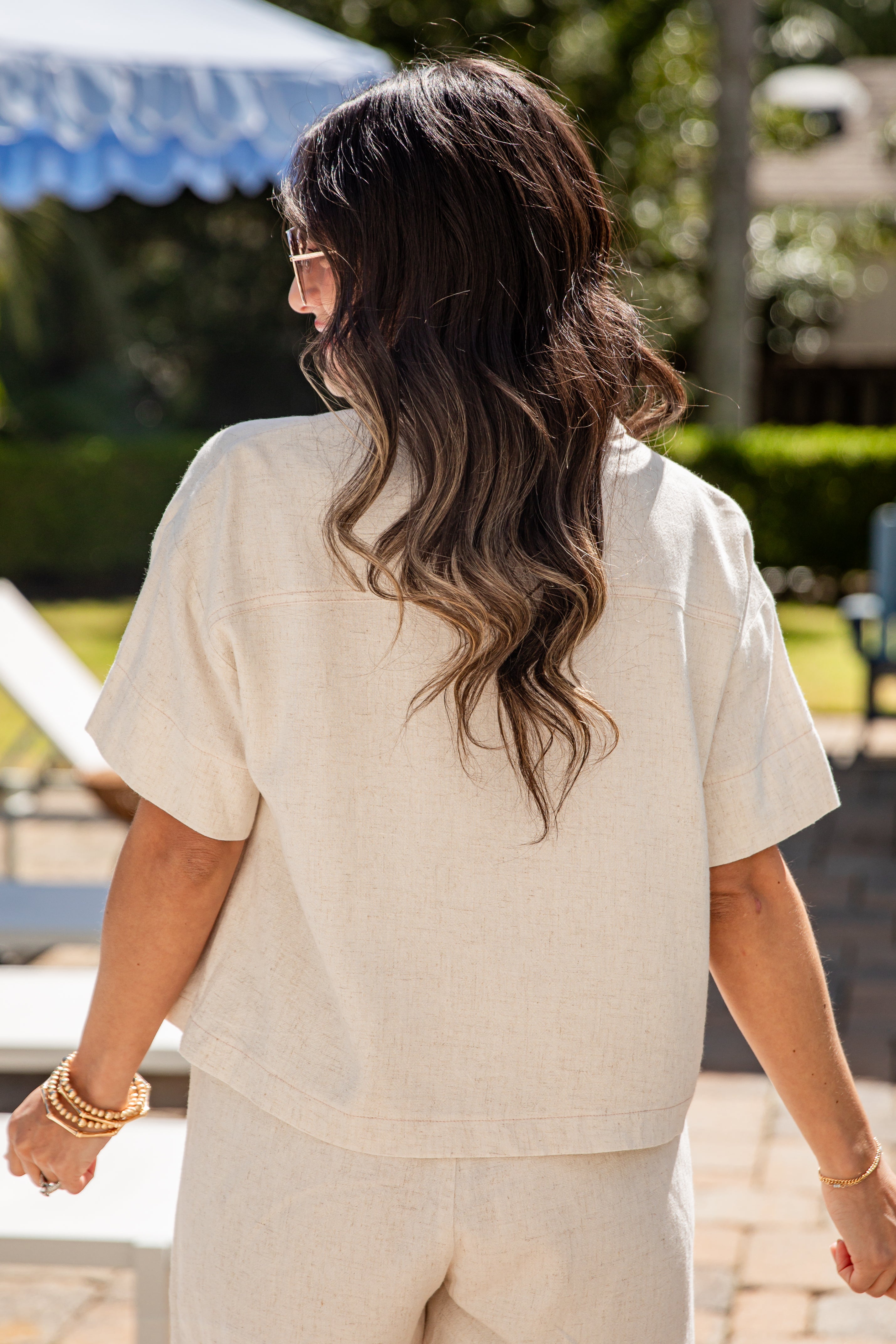 Woman in a beige outfit walking outdoors with a blurred background