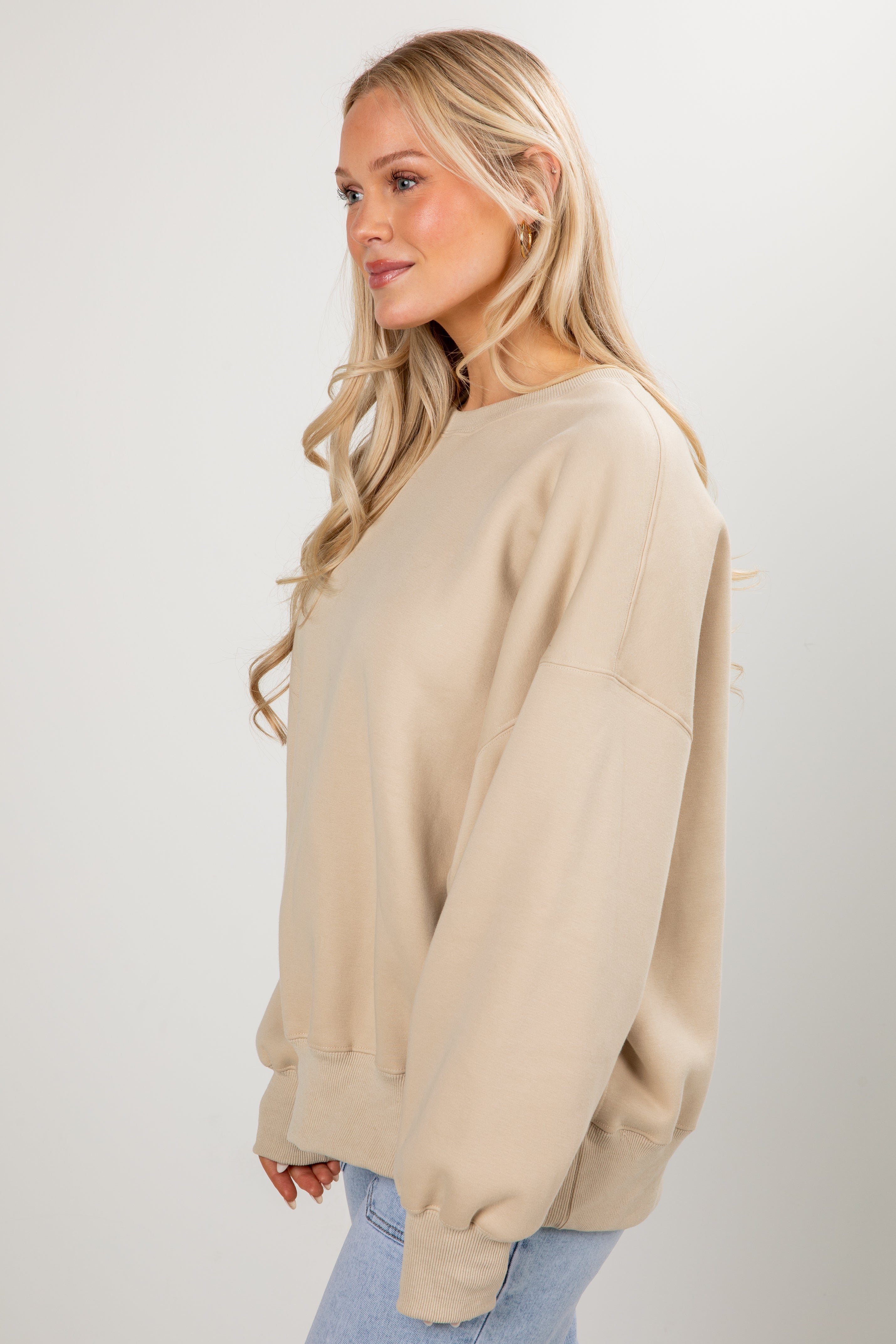Woman wearing a beige sweater against a white background