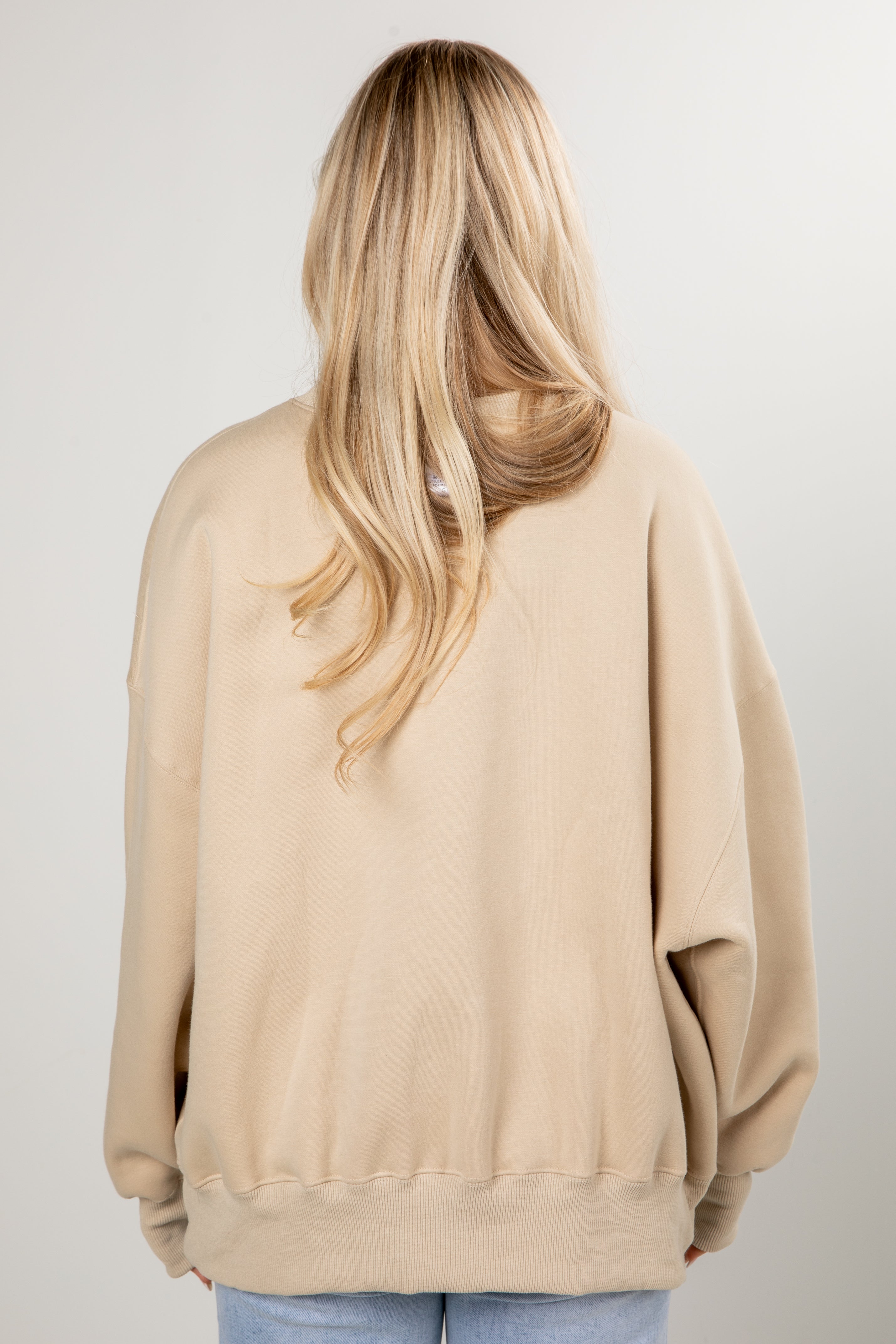 Person wearing a beige sweatshirt on a plain background