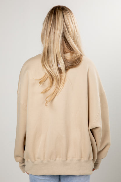 Person wearing a beige sweatshirt on a plain background