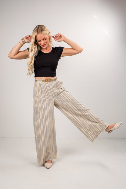 Woman wearing a black top and beige striped pants on a white background