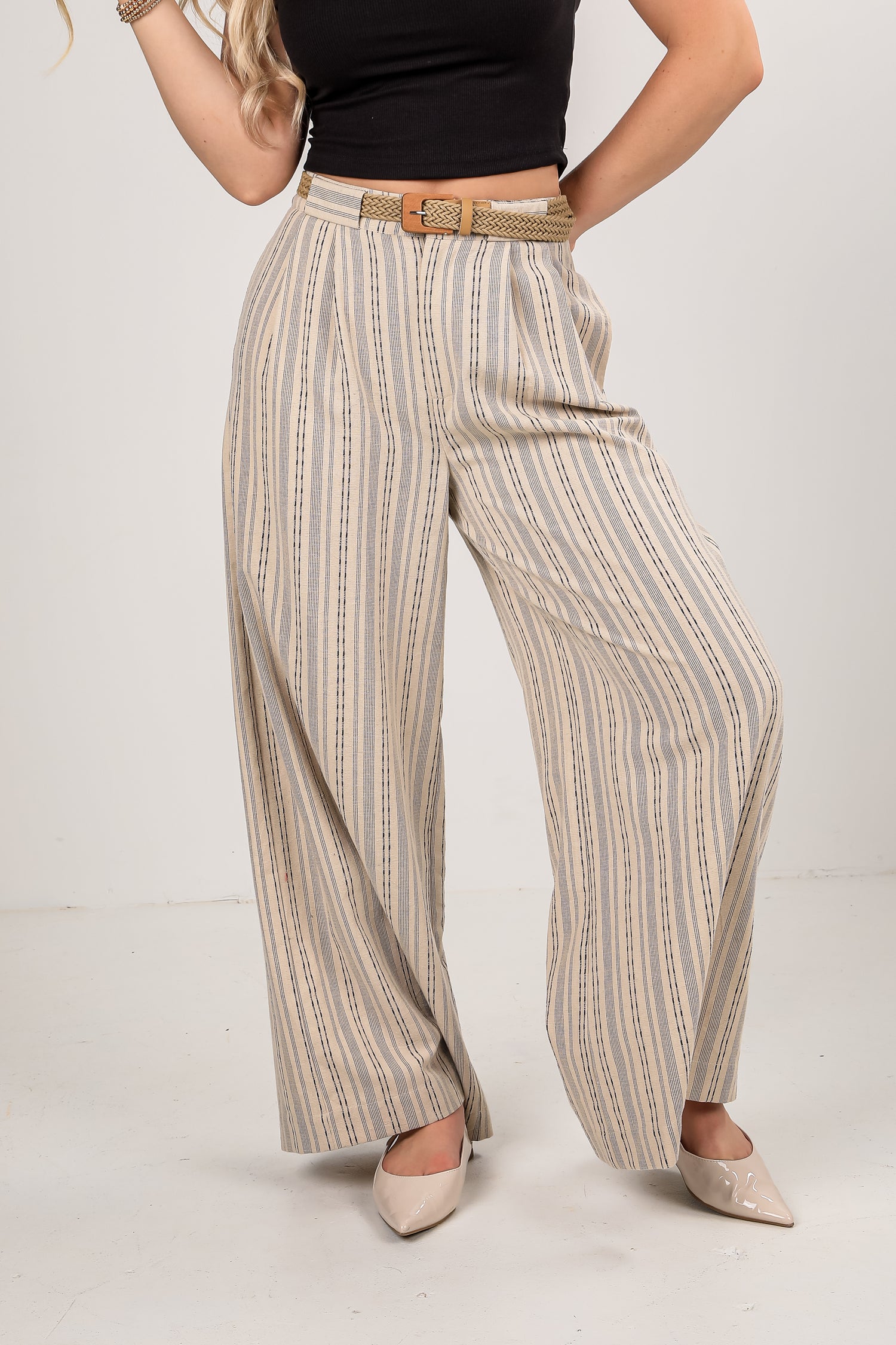 Person wearing striped pants with a belt on a plain background