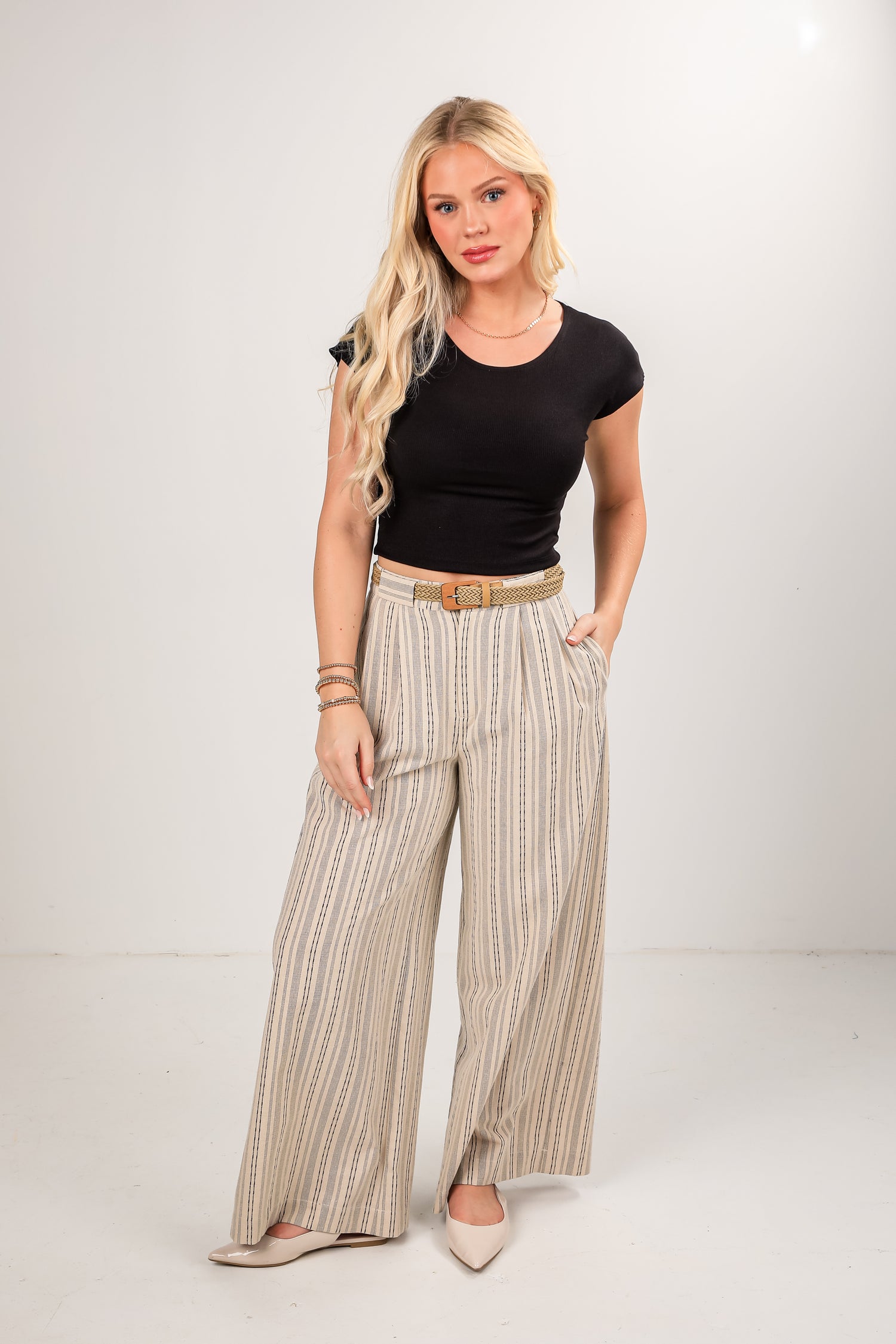 Woman wearing a black top and striped pants on a white background