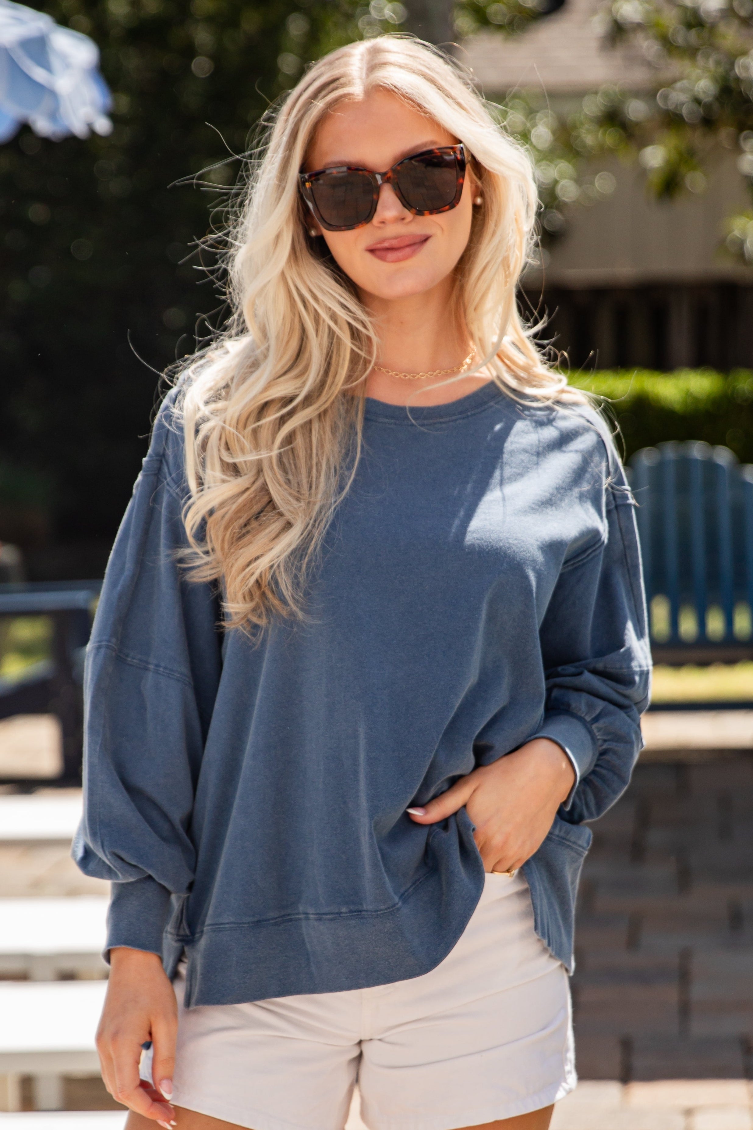 Woman wearing a blue sweater and white shorts outdoors