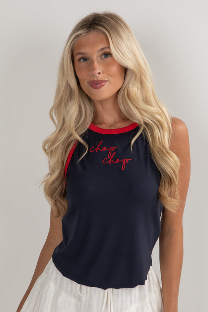 Woman wearing a navy sleeveless top with red trim and &
