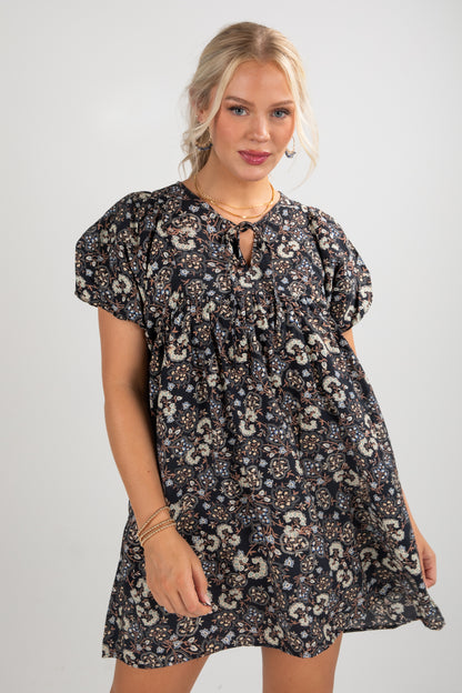 Woman wearing a floral patterned dress on a plain background