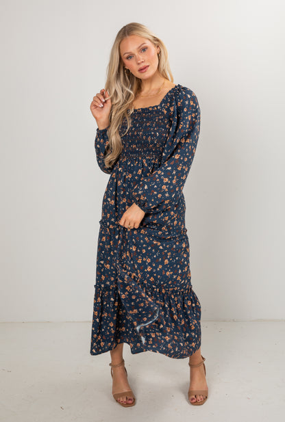 Woman wearing a navy floral dress against a white background