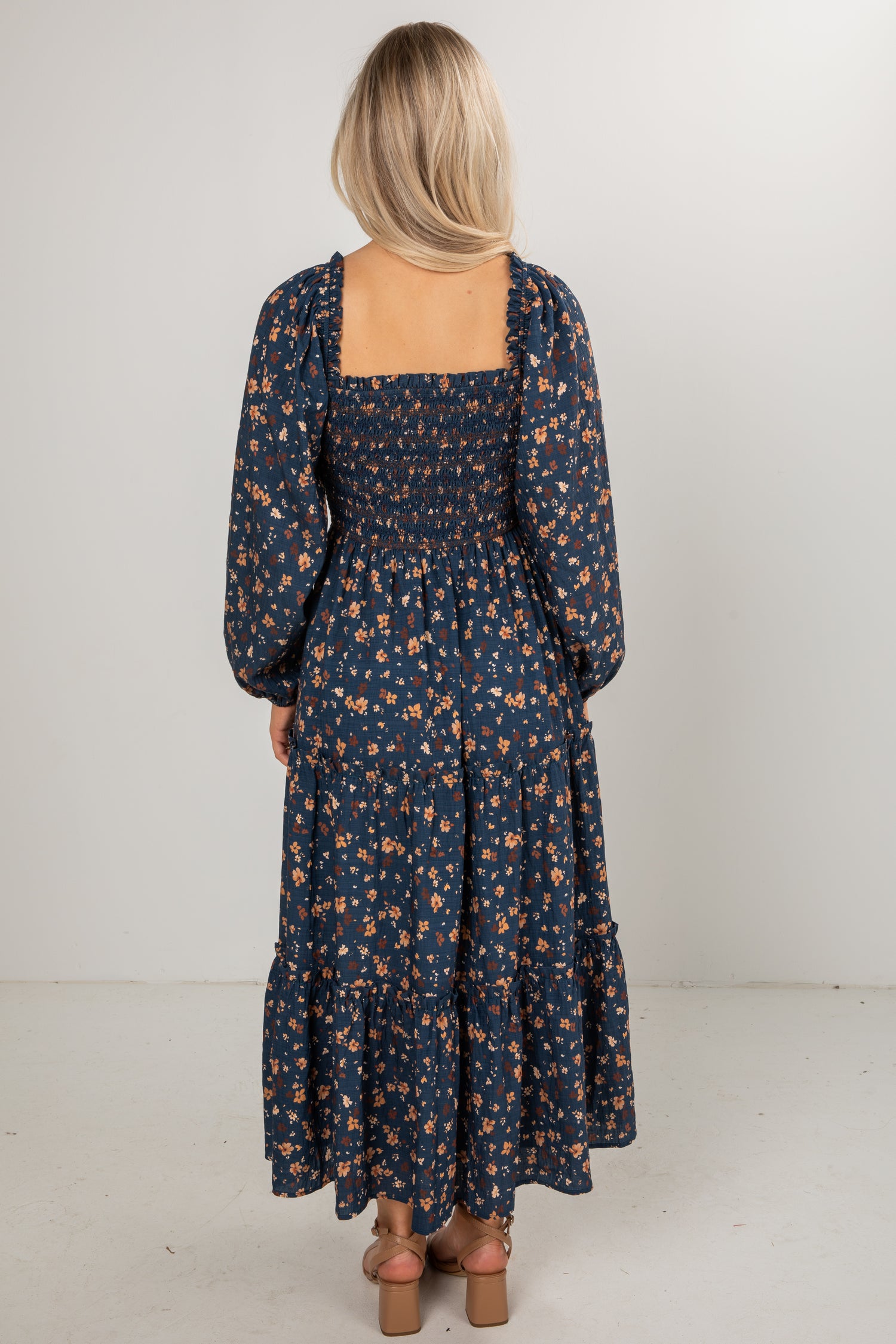 Woman wearing a long floral dress with a plain background