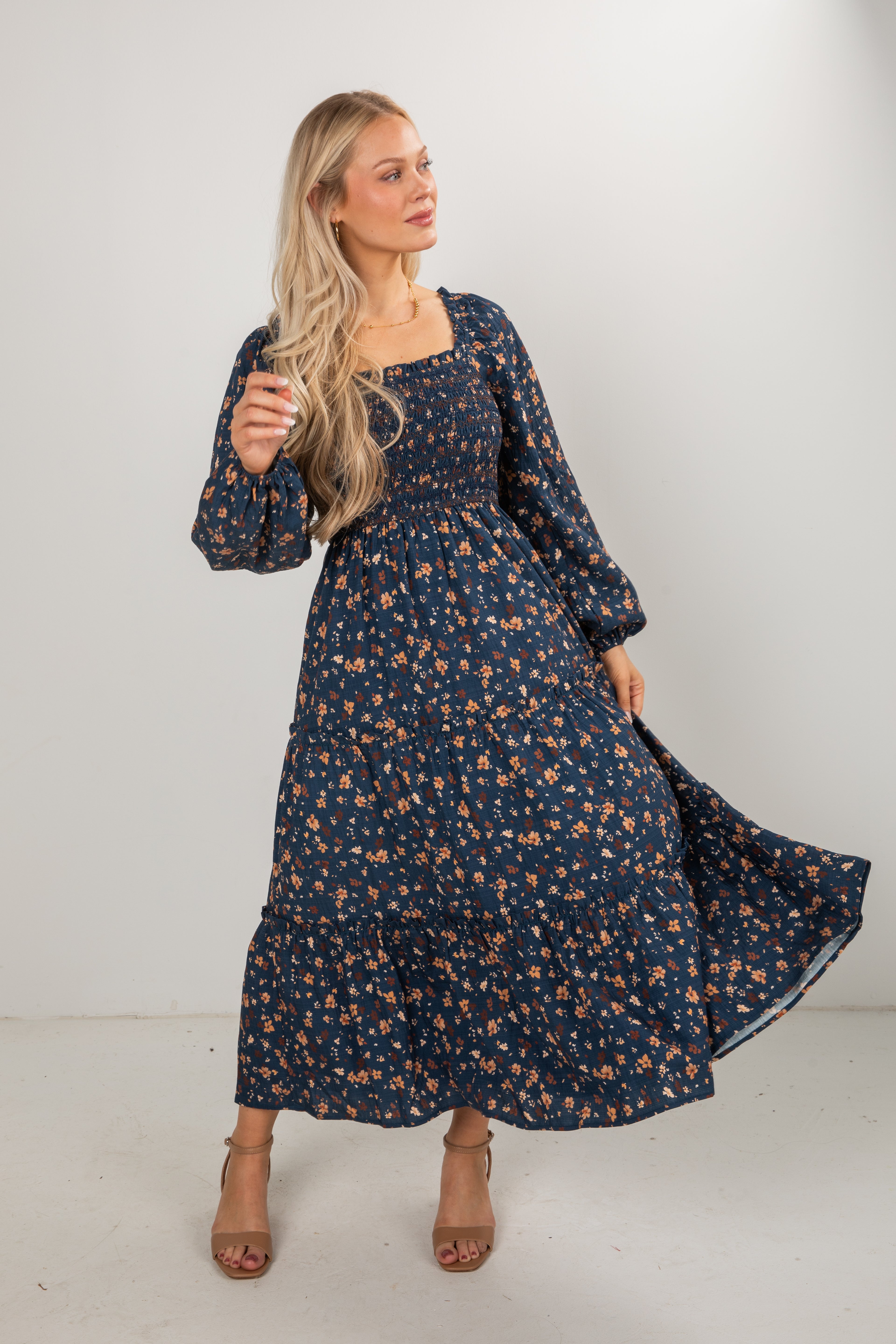 Woman wearing a long floral dress against a white background