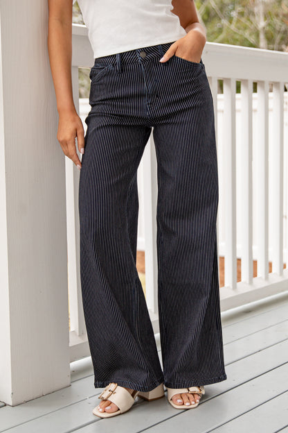Person wearing black pinstripe pants on a wooden deck