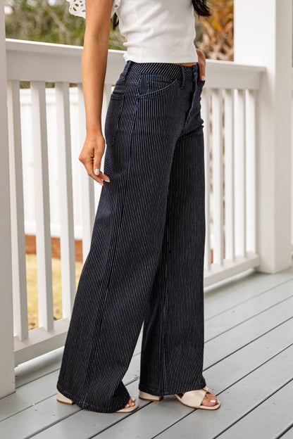 Person wearing black pinstripe pants on a wooden deck