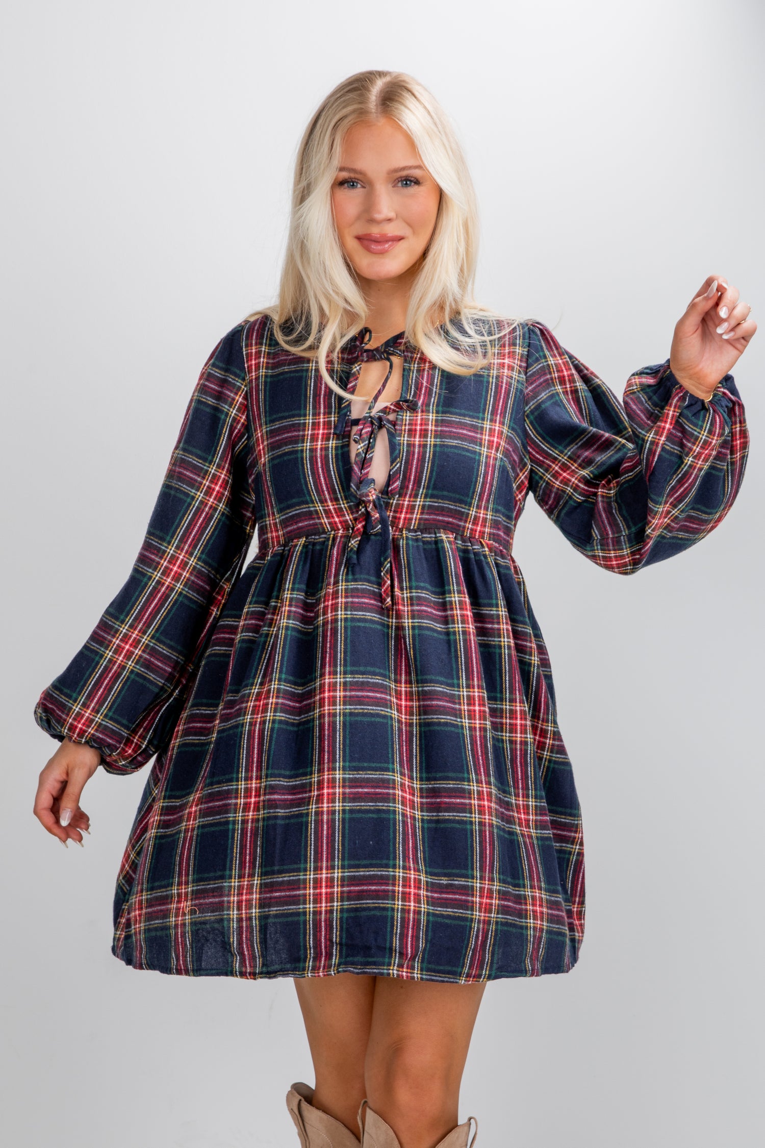 Woman wearing a plaid dress with long sleeves on a plain background
