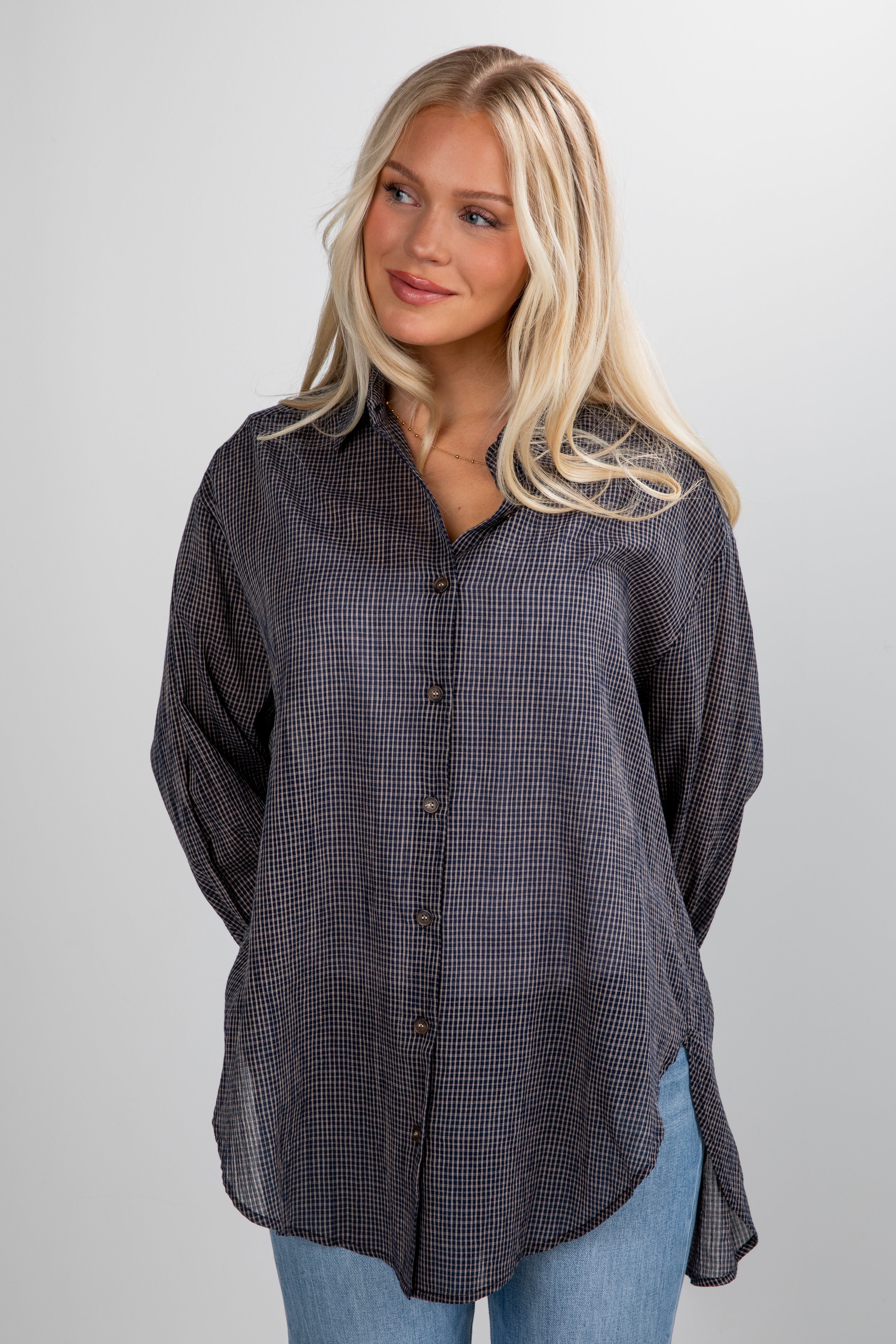 Woman wearing a dark checkered shirt against a plain background