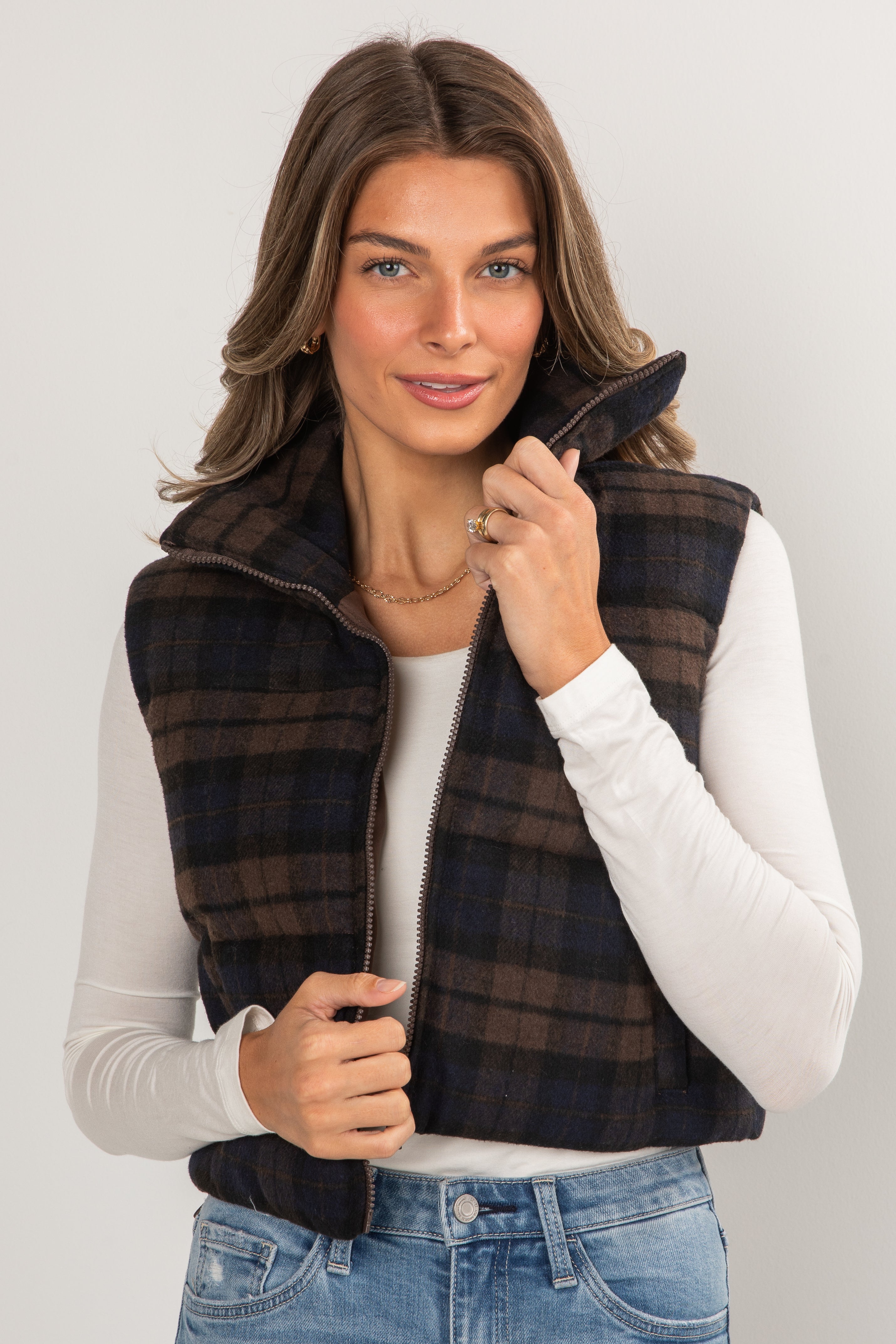 Woman wearing a plaid vest over a white shirt with a plain background