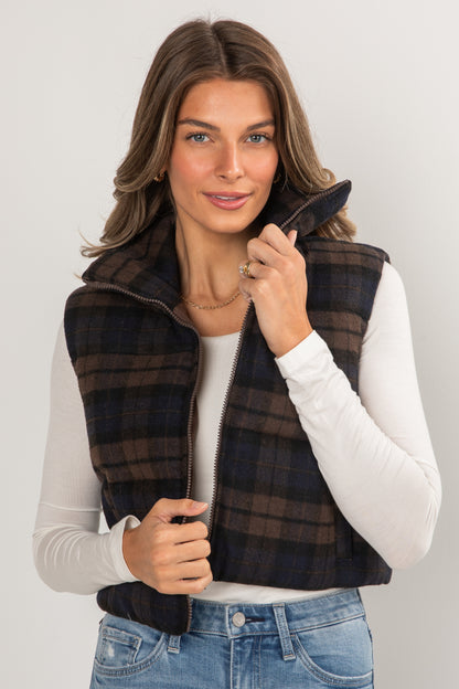Woman wearing a plaid vest over a white shirt with a plain background