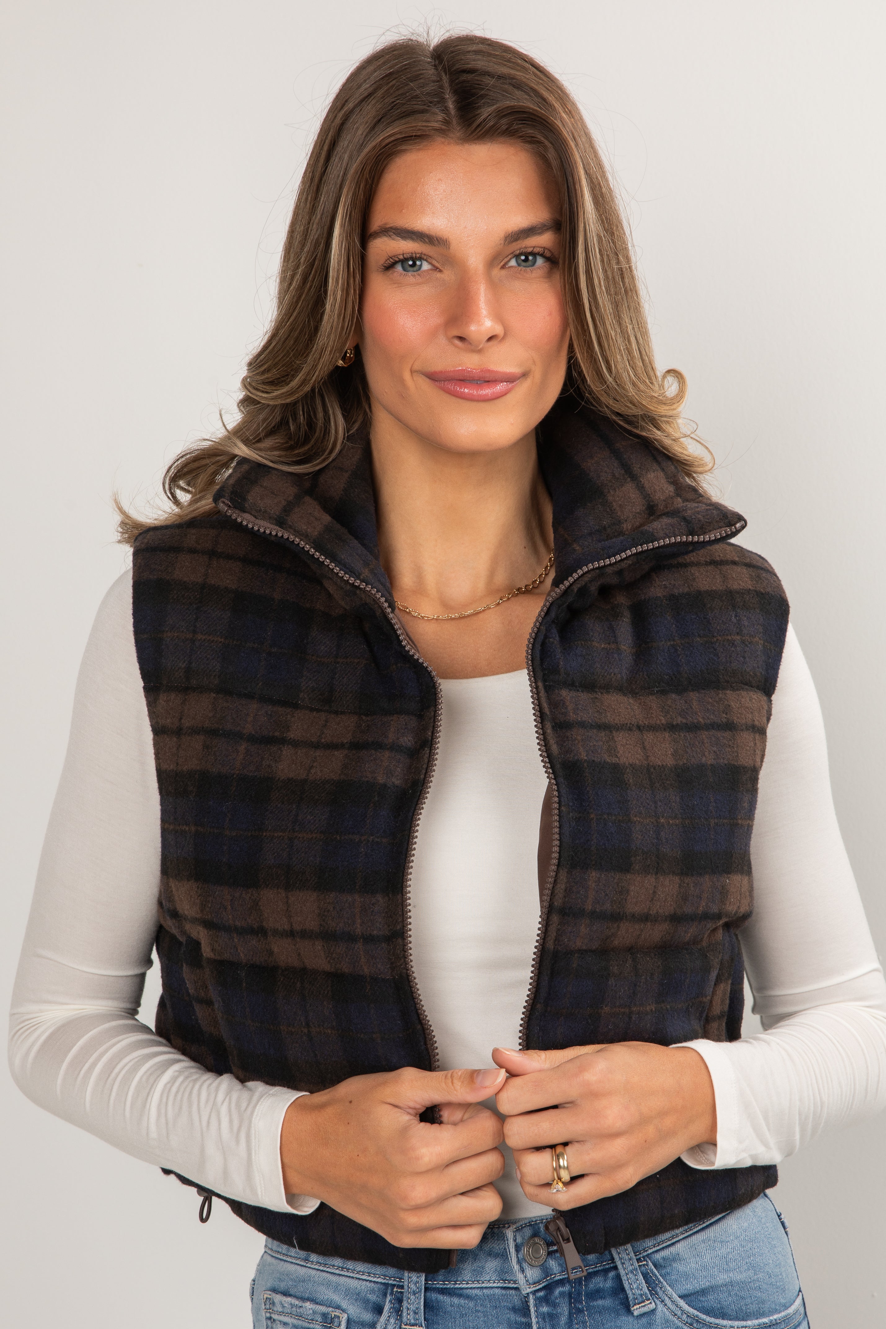 Woman wearing a plaid vest over a white shirt on a plain background