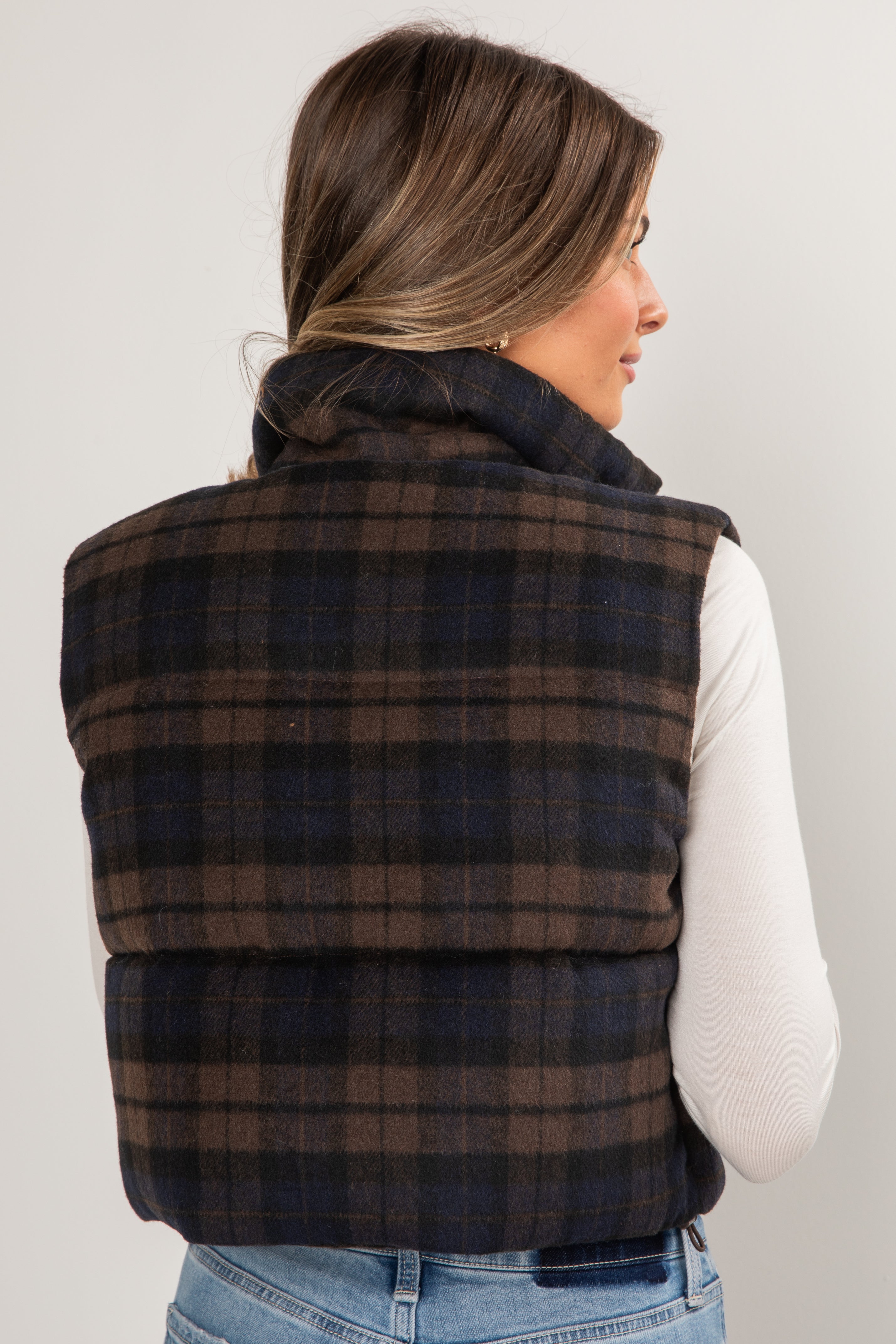 Person wearing a plaid puffer vest on a plain background