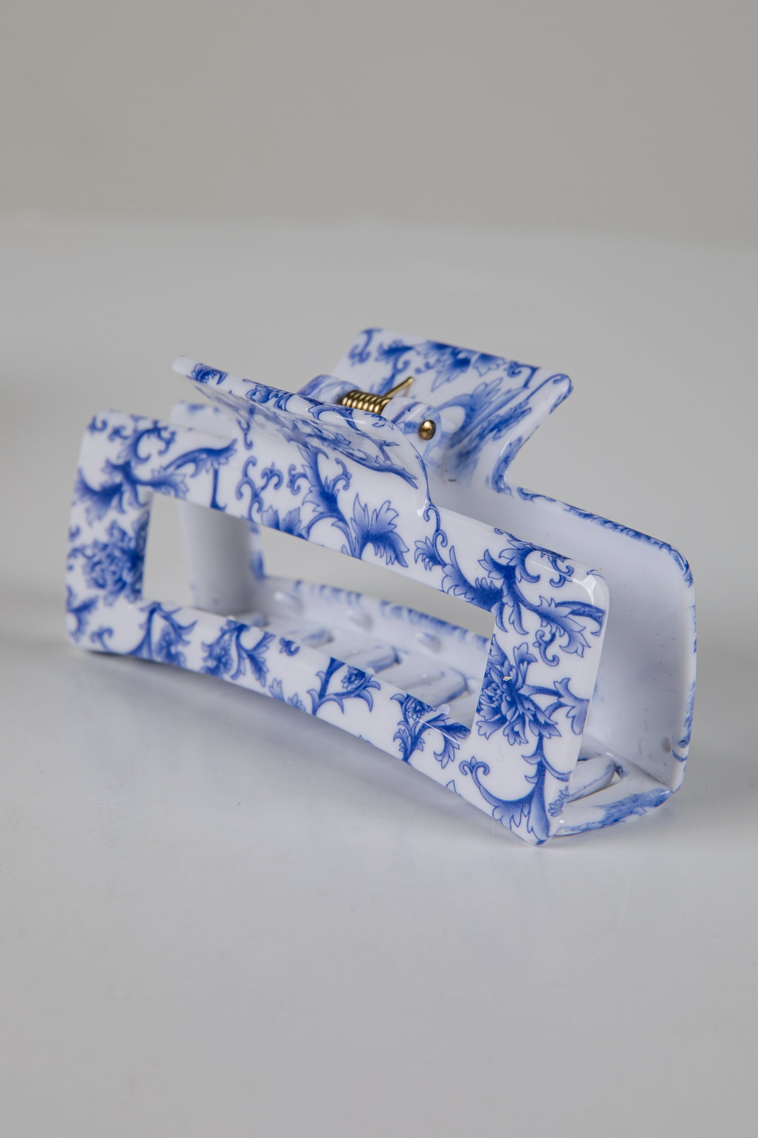 Blue and white floral patterned clutch bag on a gray background