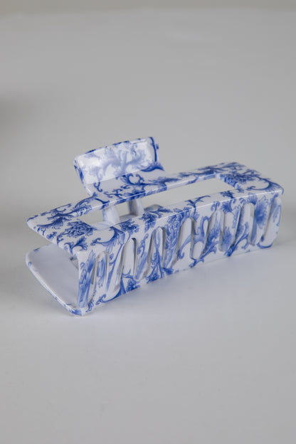 Blue and white marbled hair clip on a gray background