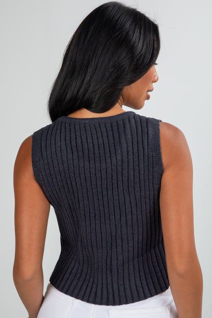 Woman wearing a dark ribbed knit sleeveless top against a plain background